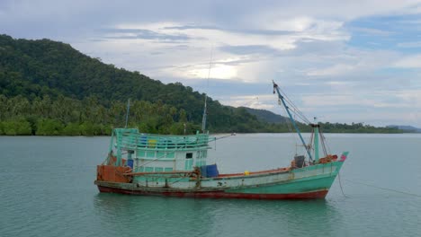A-static-shot-of-an-old-fisherman-boat,-anchored-at-sea-near-an-island