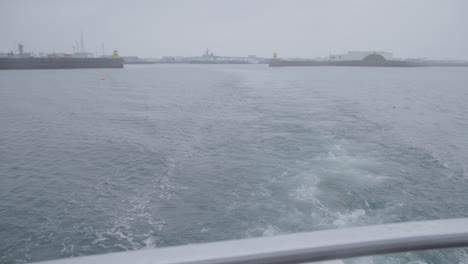 Floating-away-from-Reykjavik-harbor-on-cloudy-day-seen-from-stern-of-yacht