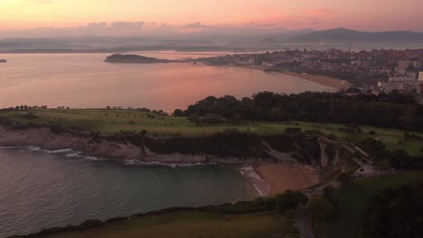 Santander-Spain-panoramic-aerial-drone-view-of-the-cityscape-with-the-lighthouse-over-the-cliff-and-sand-beach-during-sunset