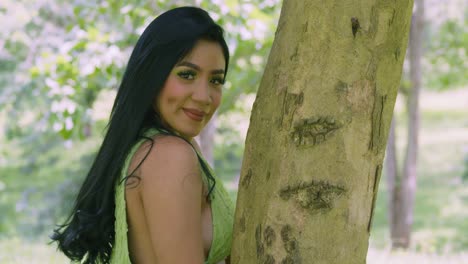A-young-woman-in-a-green-dress-hugs-a-tree-trunk-in-a-tropical-park-on-the-Caribbean-island-of-Trinidad