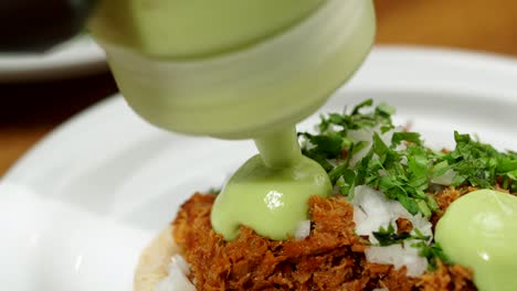 Putting-guacamole-dressing-on-mexican-beef-taco-of-carnitas