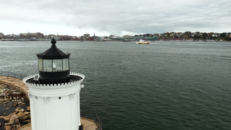 Gorgeous-aerial-shot-of-Bug-Light-Lamp-with-a-ferry-cruising-past-the-city-in-the-background