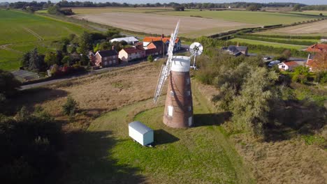 Billingford-Windmill-at-farmland-area-with-house-and-roads-in-Diss,-Norfolk---aerial-drone-rotation-tracking-shot