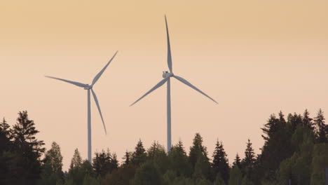 GOLDEN-HOUR,-DAWN---Wind-turbines-jutting-up-out-of-a-forest,-Sweden