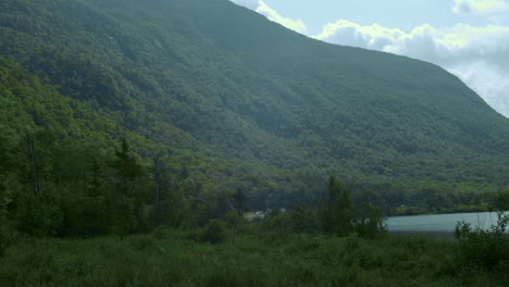 Green-mountains-slope-down-to-a-calm-lake-as-the-camera-pans