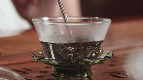Adding-hot-water-into-authentic-glass-bowl-with-Chinese-green-tea-leaves