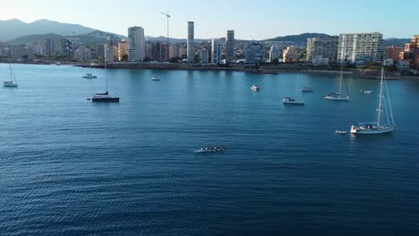 A-rowing-boat-and-yachts-sail-on-the-sea-of-Alicante,-Spain