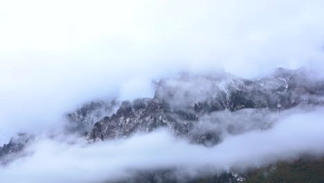 Misty-winter-day-on-Alps-mountain,-the-fog-has-fallen-over-high-peaks,-time-lapse