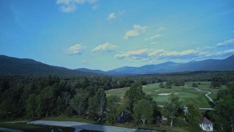 A-wide-angle-panning-shot-of-the-white-mountains-in-New-Hampshire-as-they-sit-beyond-a-forest-and-gold-course