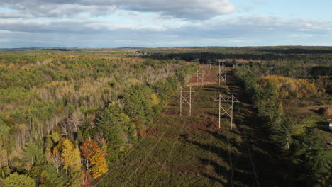 Drone-flyover-shot-of-powerlines-running-through-a-forest-in-Maine