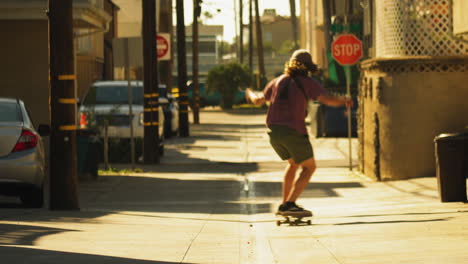 Skater-riding-down-iconic-side-street-of-Los-Angeles,-back-view