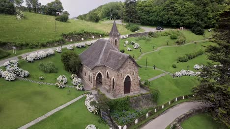 Aerial-view-crossing-roof-of-Villa-Nogues-rural-little-stone-church-with-slate-roof,-moving-closer-to-tower-spire