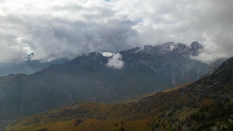 Fliegen-über-Alpenberge,-Die-Im-Herbst-Mit-Buntem-Laub-In-Wolken-Und-Nebel-Bedeckt-Sind