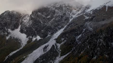 Misty-mountain-landscape-with-fog-over-high-peaks-of-the-Alps-and-slopes-covered-in-snow