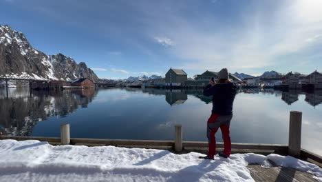 Tourist-taking-a-panoramic-picture-with-smartphone-off-the-scenery-Landscape-inside-the-Harbor-of-Svolvaer-on-a-sunny-day-with-blue-Sky,-Lofoten-Island