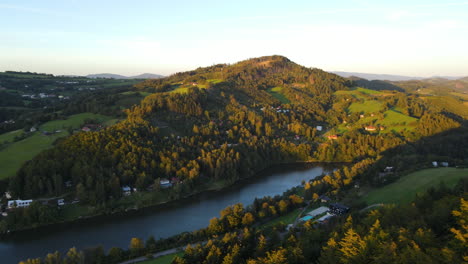Panoramablick-Auf-Einen-Damm-Inmitten-Einer-Bergregion-Mit-Hügeln-Und-Wäldern-Rundherum-Mit-Der-Sonne-Im-Hintergrund