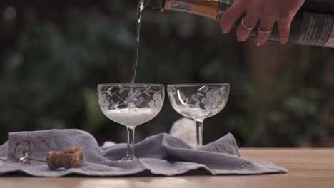Servieren-Einer-Schicken-Champagnerflasche-In-Zwei-Glasbechern-Auf-Einem-Tisch-Im-Freien