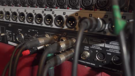 A-Panning-Shot-of-the-Backside-of-a-Music-Mixer-with-lots-of-Plugs-and-Cables