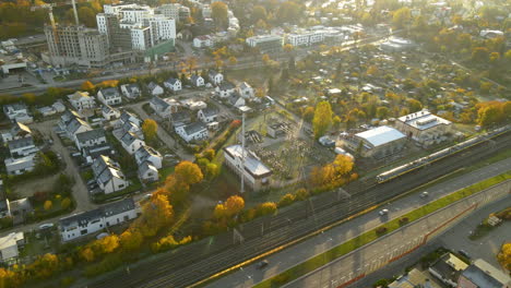 Aerial-Following-passenger-train-moving-on-railroad-in-autumn-through-urban-district-of-Gdynia-city-at-sunrise---top-view