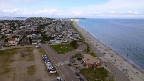 Rising-aerial-view-over-crowded-Nantasket-beach-along-coastal-town-of-Hull-at-Massachusetts,-USA