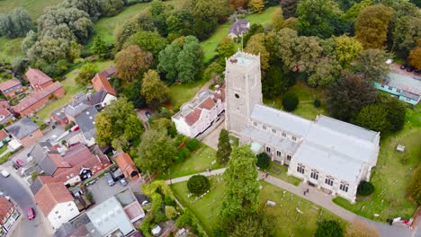 St-Michael's-Church-with-urban-town-in-Framlingham,-England---aerial-drone-rotation-tracking-shot