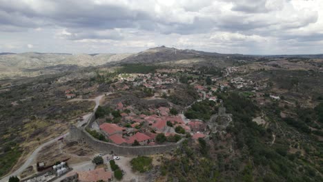 Drone-aerial-panoramic-view-of-Sortelha-historic-village-and-wind-turbines-in-natural-landscape,-Portugal