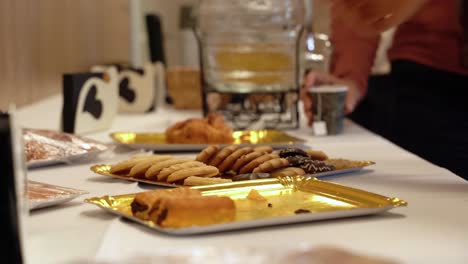 Hands-Of-Guests-Picking-Up-Baked-Cookies-From-Metal-Tray-On-The-Table