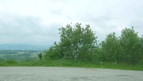 Car-side-window-view-of-the-countryside,-with-a-village-in-the-distance