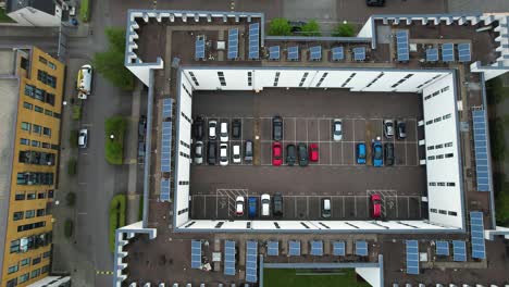 Dolly-right-aerial-view-above-energy-efficient-high-rise-solar-panel-rooftop-with-private-carpark