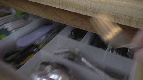 Clip-of-a-hand-grabbing-a-fork-in-a-kitchen-drawer