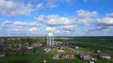 Flying-toward-a-water-tower-in-a-suburban-neighborhood-on-a-cloudy-day-with-blue-skies-4K
