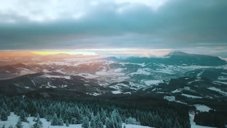 Aerial-shot-of-the-sun-rising-in-Mala-Fatra-mountains-covered-in-snow-on-a-cloudy-day,-in-Slovakia