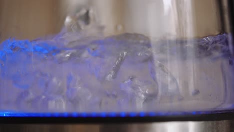 Water-boiling-inside-of-a-illuminated-bottle,-shallow-focus-close-up,-slowmo