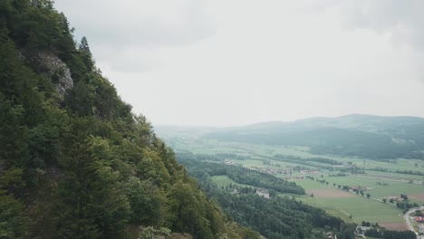 Drone-shot-of-a-german-woodland-and-mountains-in-Pidingerau,-Upper-Bavaria,-Germany,-on-a-cloudy-day