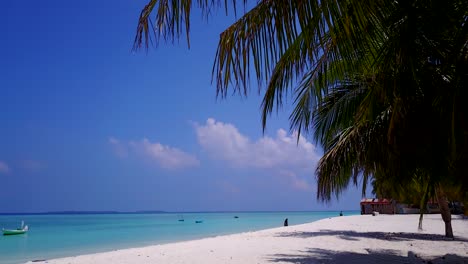 Escena-Tropical-De-Maldivas-Con-Hojas-De-Palma-Cercanas-Y-Mar-Turquesa,-Bañista-Caminando-A-Distancia-4k