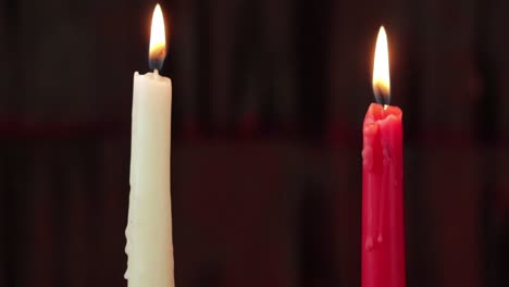 Two-burning-candles,-white-and-red,-steadycam