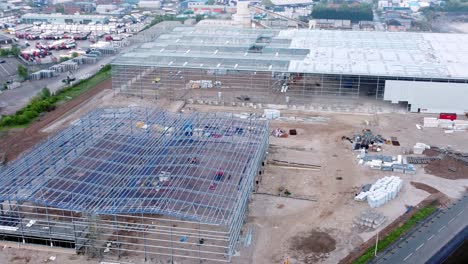 Incomplete-industrial-building-construction-site-steel-framework-aerial-view-zoom-in