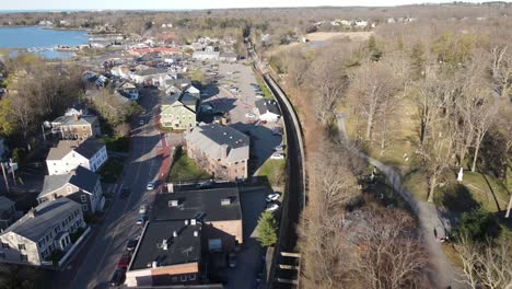 Drone-pullback-view-of-parking-areas,-harborside,-roadways-and-commercial-area-of-Hingham,-MA-USA