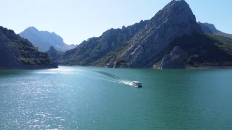 Filmischer-Drohnenclip-über-Einem-Exotischen-See-Und-Einem-Boot,-Das-Sich-Durch-Das-Wasser-Des-Riaño-Sees-In-Castilla-Y-Leon,-Spanien,-Bewegt