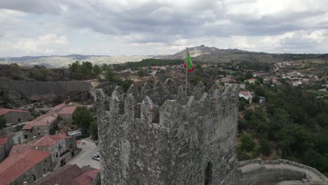 Portuguese-Flag-at-Hilltop-towering-castle-of-Sortelha,-Portugal