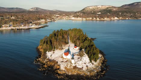 Aerial-flyby-and-tilt-down-over-snow-covered-Curtis-Island-Lighthouse-at-sunrise-with-long-shadows-in-the-snow