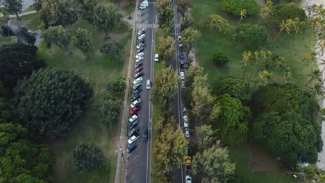 4K-cinematic-overhead-drone-shot-of-cars-driving-through-Queen-Kapi'olani-Park-near-Waikiki-in-Oahu