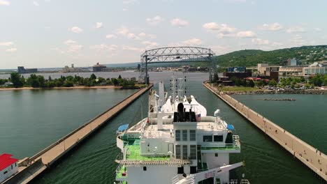 Cargo-vessel-carrying-wind-turbine-blade-propellers-approaching-Duluth-Lift-Bridge-in-Minessota,-aerial
