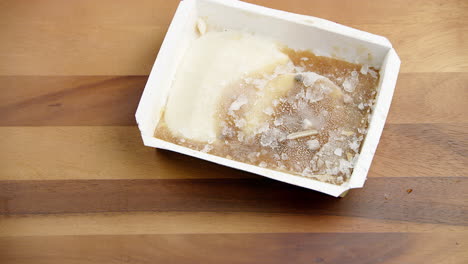 Lebensmittelverschwendung-Tiefkühlkost-Snackbox-In-Einem-Weißen-Behälter,-Der-Auf-Einen-Esstisch-Geworfen-Wird