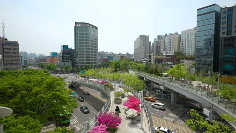 The-Seoullo-7017-skygarden-with-pedestrians,-trees-and-flowers-on-an-elevated,-linear-park-above-the-highway
