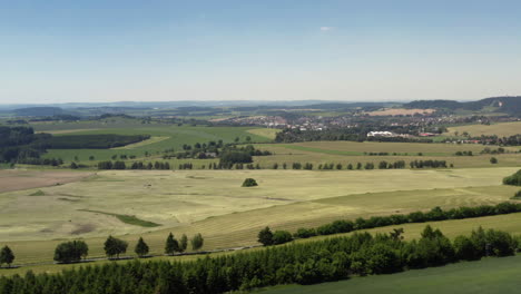 Rolling-hills-and-freshly-harvested-hay-dominate-the-beautiful-landscape-of-rural-Czech-Republic,-aerial-rise