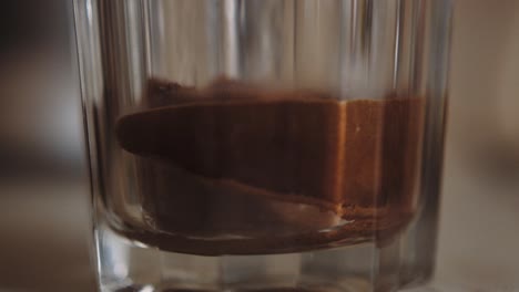 Instant-Kaffeepulver-In-Transparentem-Glas-Gewässert,-Nahaufnahme-Mit-Flachem-Fokus,-Zeitlupe