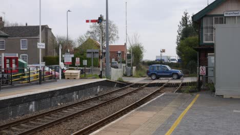 Cars-crossing-the-rail-tracks-at-an-old-village-railway-station-in-England