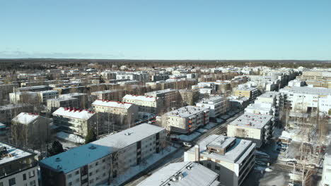 Aerial,-reverse,-drone-shot,-around-snowy-streets,-apartment-buildings,-leafless-trees,-in-the-cityscape-of-Joensuu,,-on-a-sunny,-winter-day,-in-Pohjois-Karjala,-Finland