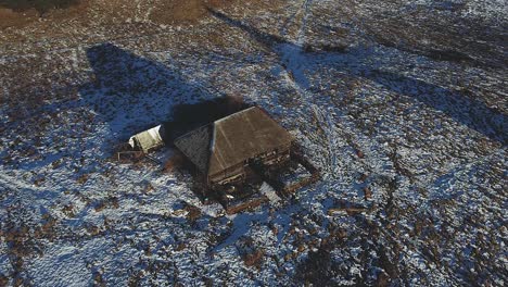 Tracking-right-left-drone-shot-of-a-small-cabin-in-the-wintertime